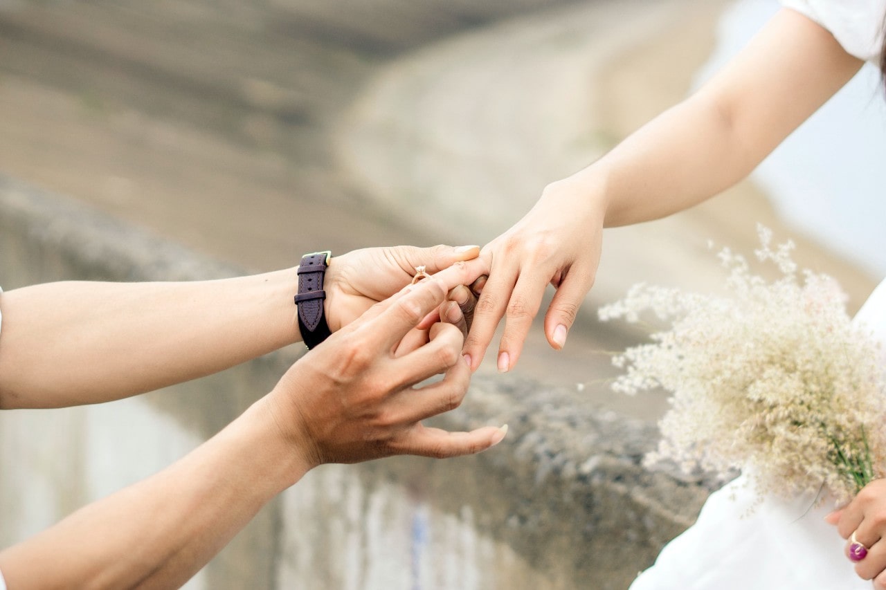 a man placing an engagement ring on a woman’s finger a man placing an engagement ring on a woman’s finger