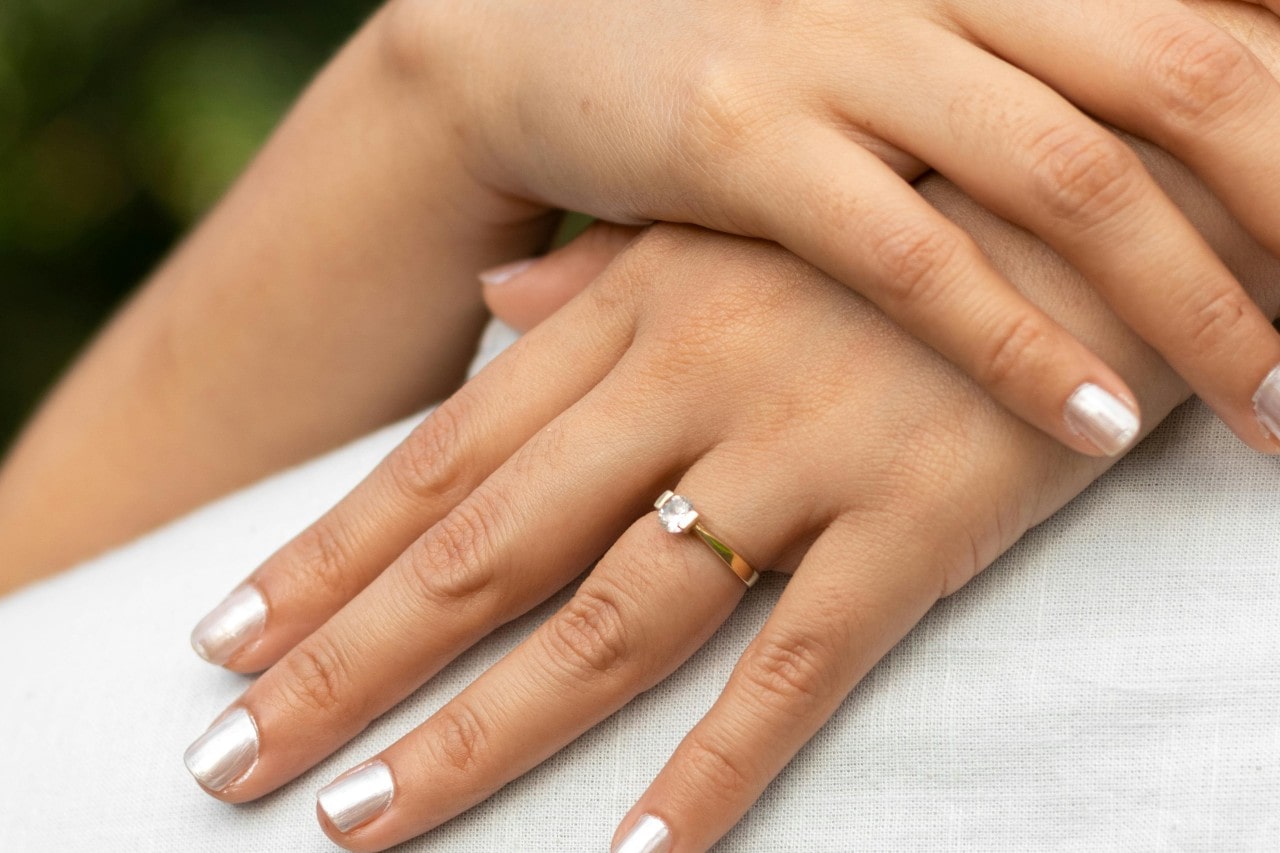 a woman’s hands with silver nails wearing a solitaire engagement ring a woman’s hands with silver nails wearing a solitaire engagement ring