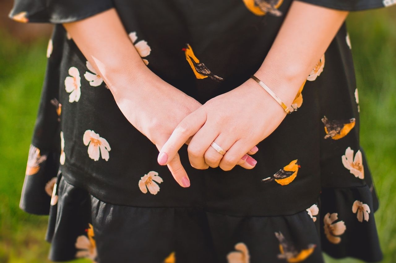 A close-up of a woman wearing a simple gold bracelet and matching ring. A close-up of a woman wearing a simple gold bracelet and matching ring.