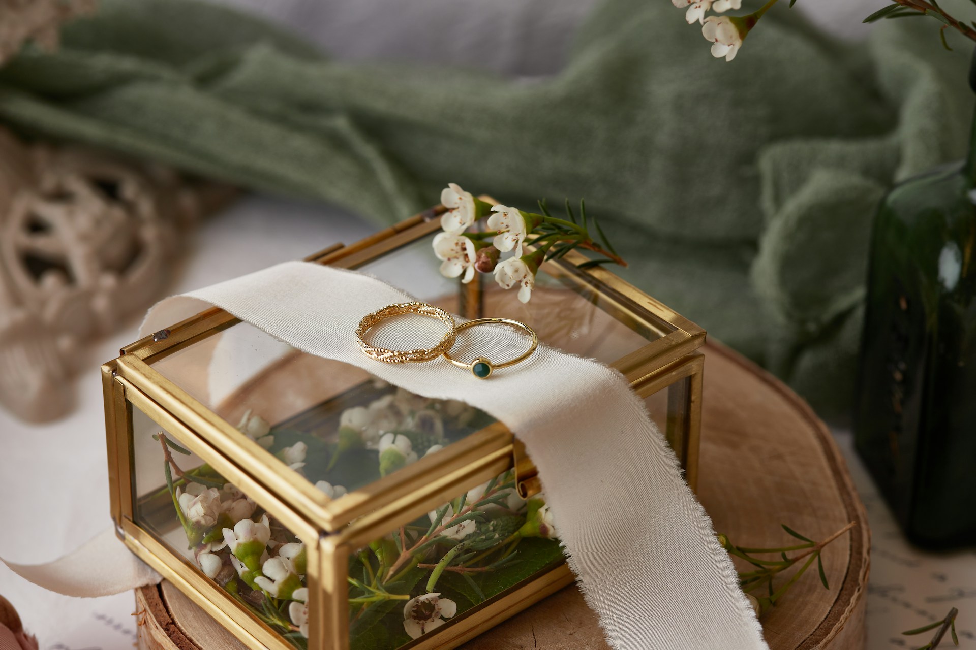 A view of a simple yet elegant jewelry box full of flowers, with two gold wedding bands displayed on top. A view of a simple yet elegant jewelry box full of flowers, with two gold wedding bands displayed on top.